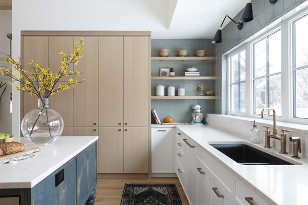 Modern kitchen with light wood cabinets, white countertops, a black sink, and decorative shelves. Custom built in Calgary by Cortina Crafted Homes
