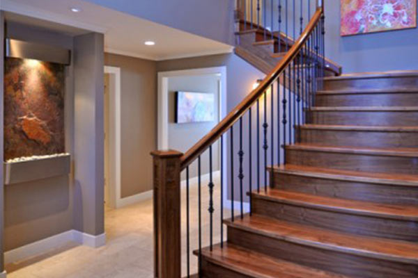 A stylish foyer featuring a wooden staircase, modern wall art, and a decorative water feature, creating an inviting atmosphere.