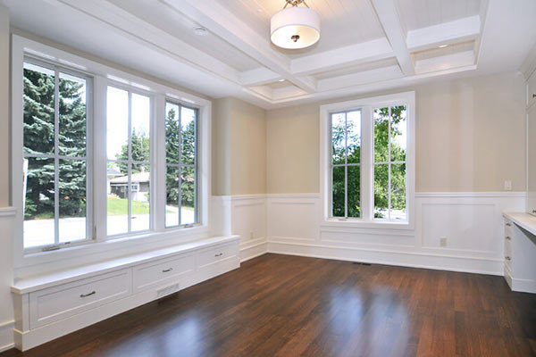 Bright, airy room with large windows, hardwood floor, and crown molding, featuring built-in seating along the window.