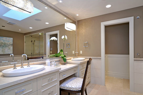 Modern bathroom featuring dual sinks, stylish lighting, a glass shower, and decorative plants, with a serene color palette.