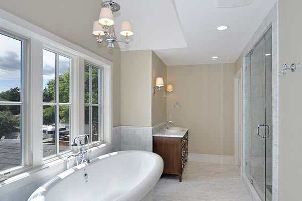 Elegant bathroom featuring a free-standing tub, modern vanity, glass shower, and ample natural light from large windows.