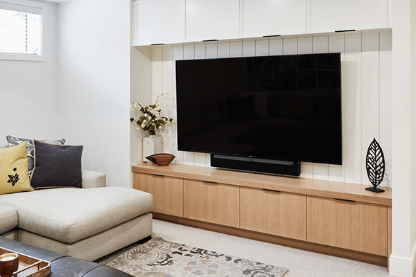 Modern living room featuring a built-in wooden tv stand, complemented by a sectional sofa inside modern farmhouse built by Cortina Custom Homes in Calgary Alberta