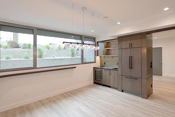 Modern interior featuring a bar with sleek cabinetry, large windows, and stylish lighting, creating a bright and airy ambiance.